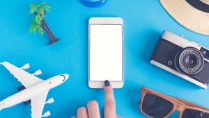 Flat lay of hand using smart phone and summer vacation items